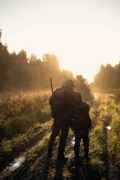 Padre e hijo cazando juntos. Caminando por la carretera después de la caza de aves . — Foto de Stock