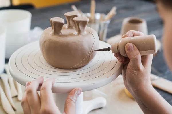 セラミックスタジオで装飾されているマグカップの底の閉鎖、。特殊な絞り工具で花瓶の表面に粘土の点や滴を作る女性の専門家の手. — ストック写真
