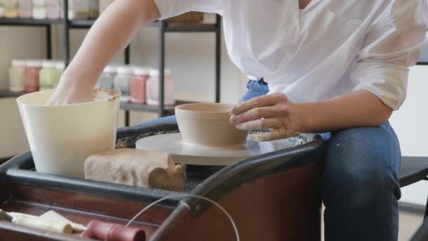 Woman working on potters wheel making dishes with their own hands. Close-up photo of dirty hands molding clay — Stock Video