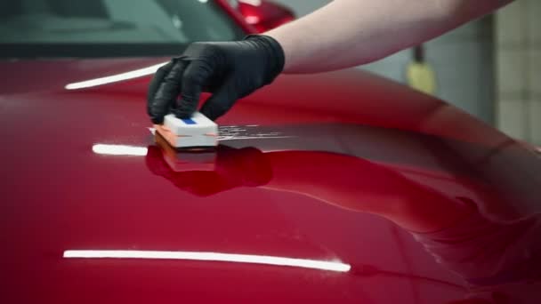 Hombre trabajador del estudio de detalles del coche aplicando recubrimiento de cerámica en la pintura del coche con aplicador de esponja — Vídeos de Stock