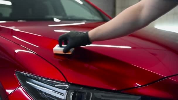 Detalhes do carro - O homem aplica revestimento nano protetor ou cera no carro vermelho. Cobrir o capô do carro com um polimento de vidro líquido. — Vídeo de Stock