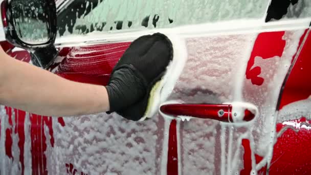 Hombre lavando un coche usando guantes de mano limpiando espuma. Primer plano de un proceso de limpieza automotriz. — Vídeos de Stock