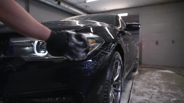 차의 자세 한 사항 - 이 남자는 손으로 특별 세탁 장갑을 끼고 차의 헤드라이트를 닦고, 클로즈업. — 비디오