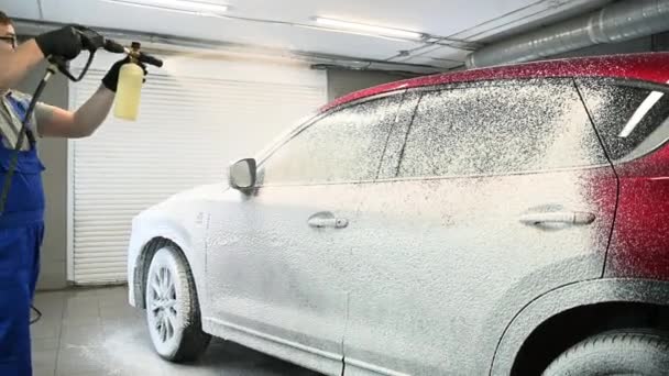 Worker covering automobile with foam at car wash. — Stock Video