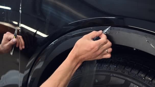 Primer plano del hombre profesional arrancar la película de vinilo después de cortarlo. coche que detalla el coche que cubre experto con la capa protectora . — Vídeo de stock