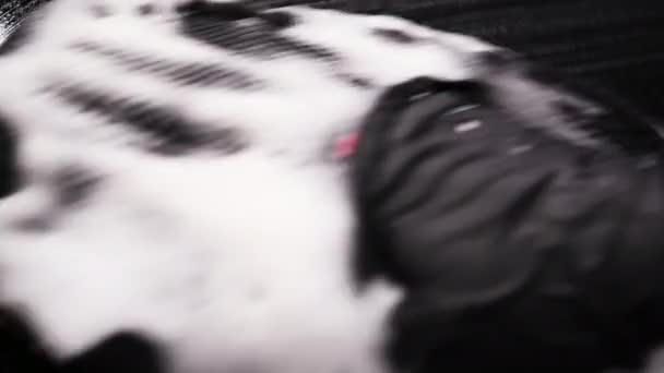 人の手のマクロ映像はワイパーを使用して落下から車の表面をきれいにする。拭き取った後に泡が破裂. — ストック動画