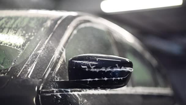 Slow motion close up of car mirror in car wash. Foam drops dripping from a side mirror of a car. — Stock Video