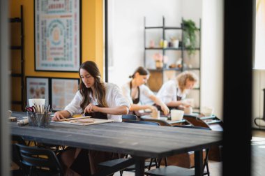 Beyaz kadın en iyi arkadaş çömlek sanatçıları seramik bir kapsül dekorasyonu yapıyorlar, sanat stüdyosunda çalışırken konuşup gülümsüyorlar..