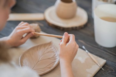 El yapımı çömlek kaplaması dekore eden kadın.