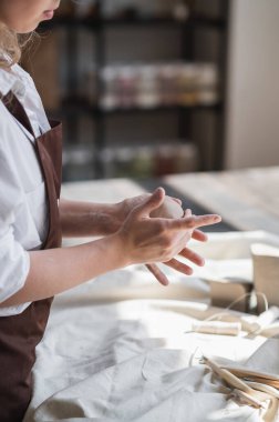 Kadın çömlekçi masadaki kil parçasını şekillendiriyor. Kadın seramik bir şey yapıyor. Sanat stüdyosunda çömlekçilik, el yapımı ve yaratıcı beceriler..
