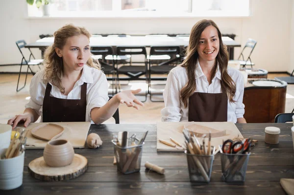 Γυναίκες αγγειοπλάστες που φτιάχνουν πήλινη κεραμική στο τραπέζι με διαφορετικά ξύλινα εργαλεία — Φωτογραφία Αρχείου