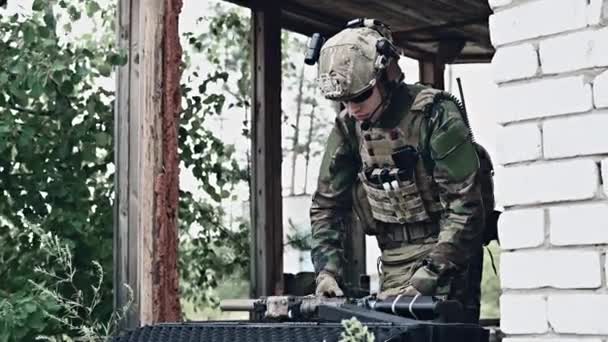 Militaire man met wapenkoffer schakelt een aanvalsgeweer uit in verwoeste stad. Concept militaire en reddingsoperatie. — Stockvideo