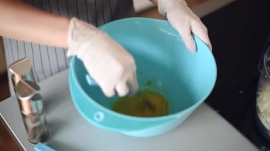 Kız çiğ yumurtaları mavi bir kasede soğanla çırpıyor. Yumurtaları çırpıyorum.