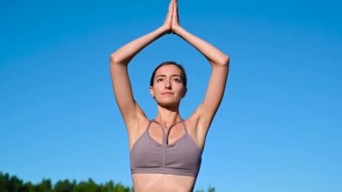 Gün doğumunda gökyüzüne karşı yoga yapan genç bir kadın. Oldukça zayıf bir kadın egzersiz yapıyor. Sağlık, meditasyon, sağlık, farkındalık konsepti.