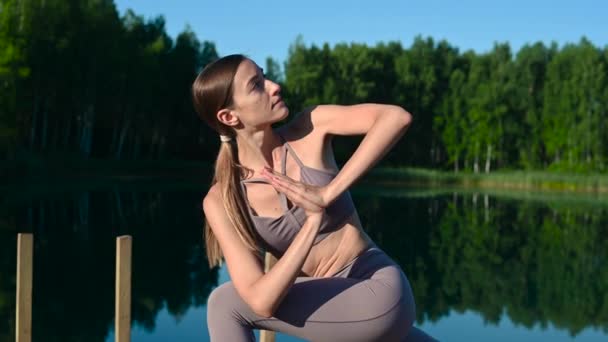 Joga odkryty asana praktyki o zachodzie słońca na molo nad jeziorem przez sport spokojna dziewczyna. — Wideo stockowe