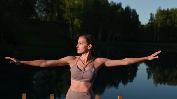 Gezonde vrouw die yoga beoefent op het meer bij zonsopgang en geniet van positieve energieën uit de natuur — Stockvideo