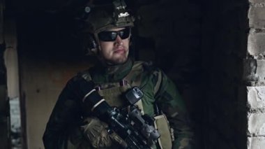 Binanın içinde duran tam teçhizatlı askerin yakın plan çekimi.