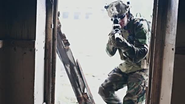 Soldat armé entrant dans le couloir du bâtiment abandonné, vérifiant les pièces. — Video