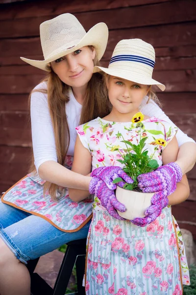 Femme et fille, mère et fille, jardinage ensemble plantant des fleurs dans le jardin. Regardant la caméra — Photo