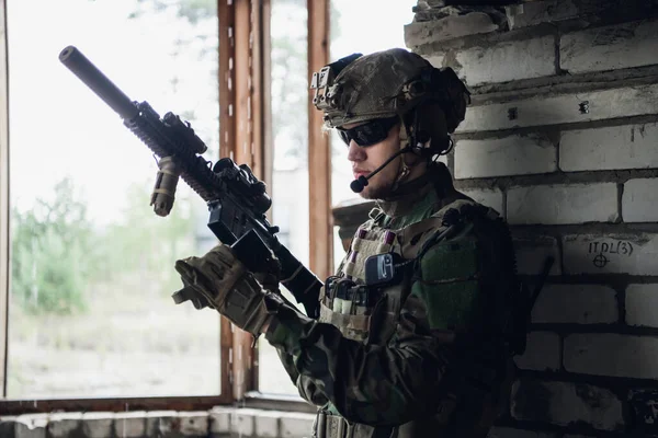 Brutal militar está sentado e limpando e preparando sua arma para a batalha. — Fotografia de Stock