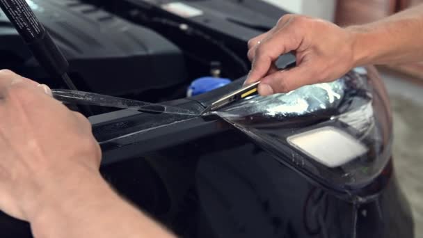 Різання плівки захисту фарби спеціальним інструментом для ножів на чорному автомобілі — стокове відео