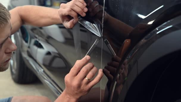Corte de película de protección de pintura con una herramienta de cuchillo especial en un coche negro — Vídeos de Stock