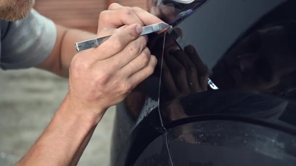 Detallando la película de protección de pintura de los hombres de corte especialista y envolver el coche en la sala de exposición de garaje, instalación de recubrimiento protector — Vídeos de Stock