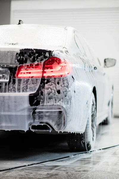 洗車場だ。車の閾値は、洗車場で白い流れる泡で覆われている. — ストック写真