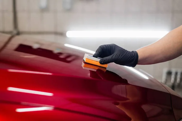 Hombre trabajador del estudio de detalles del coche aplicando recubrimiento de cerámica en la pintura del coche con aplicador de esponja — Foto de Stock