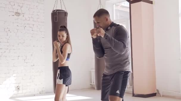 Il primo allenamento di una combattente alle prime armi nel kickboxing, l'allenatore mostra i colpi — Video Stock