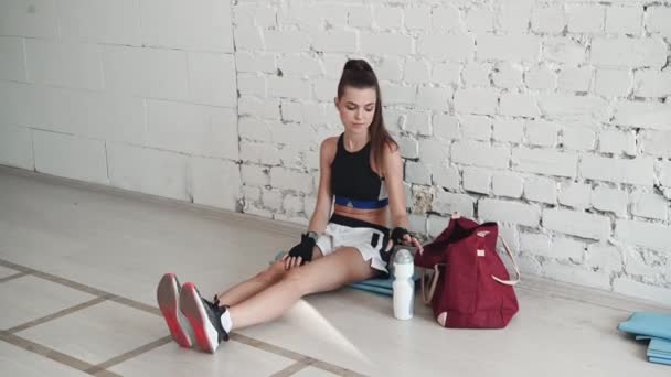 Selama sesi pelatihan seorang gadis kickboxer cantik beristirahat dan bersandar di dinding — Stok Video