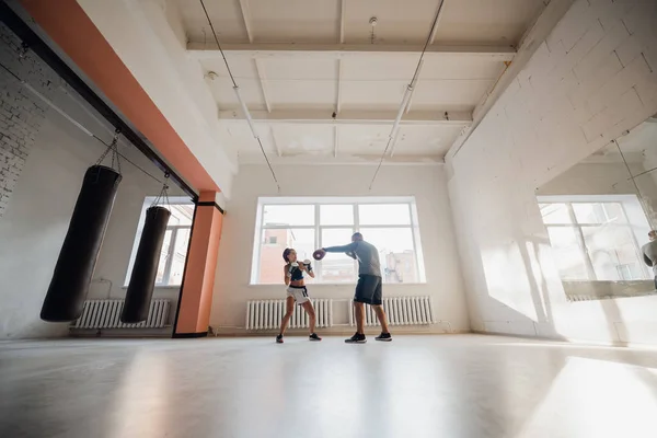 Un uomo e una donna che combattono partner si allenano nella sala di addestramento dei combattenti in guanti da boxe con le zampe — Foto Stock