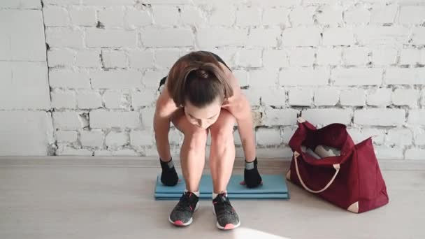 Egy fiatal lány elfáradt a boksz edzésen, és leült a falhoz pihenni és inni. — Stock videók