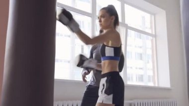 Baba küçük kızını karma dövüş sanatları yarışmalarına hazırlıyor. Kız kum torbasına vuruyor.