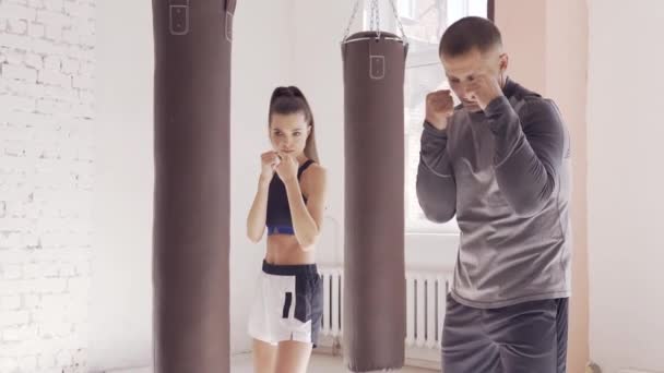Linda chica aprende técnicas de kickboxing en el gimnasio con un entrenador experimentado — Vídeo de stock