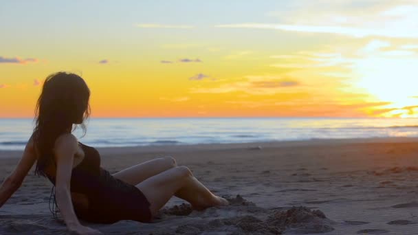 女人引诱和愉快地滚动沿着沙滩上的沙子 轻轻地笑 从直接附近和背景下 海和日落的环境 — 图库视频影像