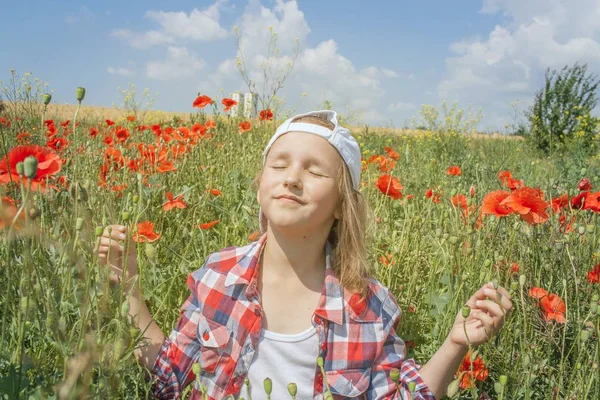 the blossoming poppies . Inner world of the child . Meditation as way of life . Relaxation in the fresh air . Portrait of the happy beautiful young woman . in the field of wheat