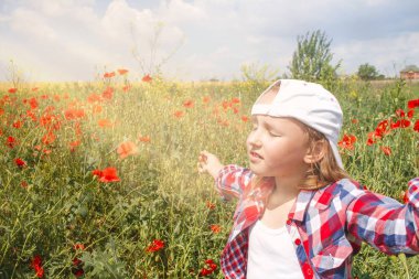 çiçek açması haşhaş. Çocuğun iç dünyası. Meditasyon yaşam biçimi olarak. Temiz havada rahatlama. Mutlu güzel genç kadın portresi. Buğday alanında 