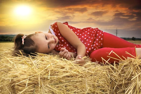 Pensive child day dreaming  . Young woman lying in hay . Little girl lying on grass . Girl playing in the sun . Loving the free . Inner world of the child . Meditation as way of life . Relaxation in the fresh air .