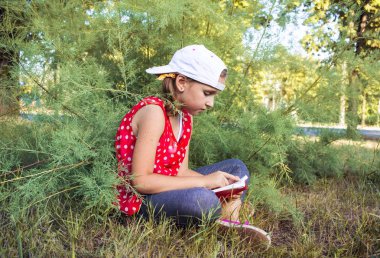 Çocuk açık havada kitap ya da İncil okuma. Sevimli küçük kız İncil okuma. Kutsal İncil'in üzerine dua genç çocuğun elleri. Çocuğun iç dünyası. Meditasyon yaşam biçimi olarak. Temiz havada rahatlama. Portre 