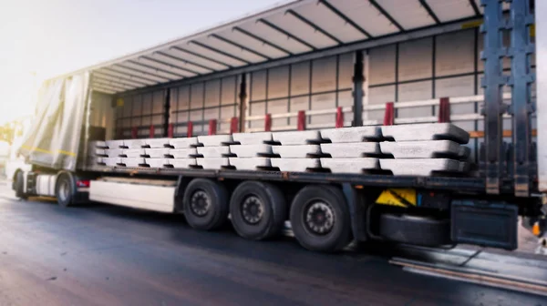 There is a loading to the truck trailer .  fastening of freight in the trailer .  Truck in unloading in warehouse .  transportation of freight Europe . industrial infrastructure . to fix freight .  Cargo container .