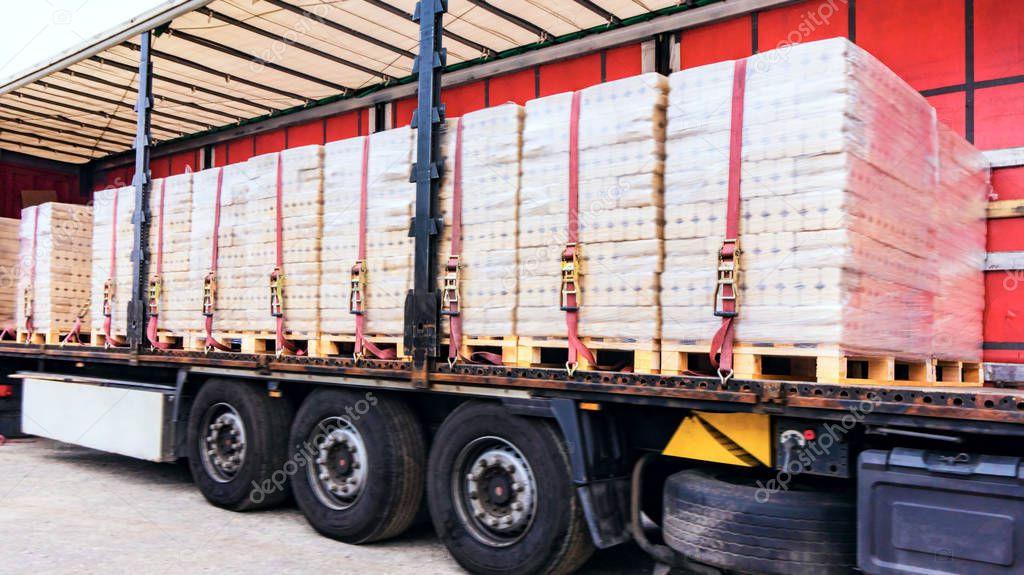  There is a loading to the truck trailer .  fastening of freight in the trailer .  Truck in unloading in warehouse .  transportation of freight Europe . industrial infrastructure . to fix freight .  Cargo container . 