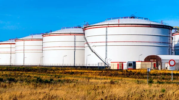 White tanks for petrol and oil in tank farm with blue sky .