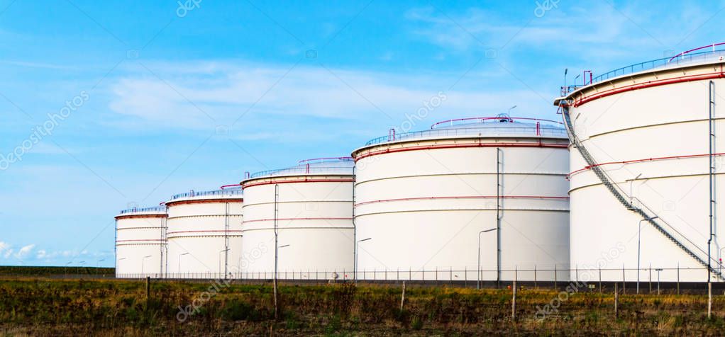 White tanks for petrol and oil in tank farm with blue sky . 