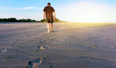 Sahada yürüyen genç adam. Yeni yükseliş. Gökten gelen ışık. Güneş doğarken dua . 