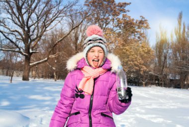 Açık portre kış parkta mutlu bir çocuk. Çocuk açık havada bulunan su içer. Kış güneşli gün. Kış etkinlik kavramı. İçmek istiyorum. doğal içecek . 