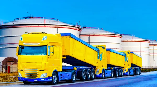 On the road a car for transportation of grain . the yellow truck with the trailer . Agricultural silos .Tank farm . Commercial transport .  truck transport container   .
