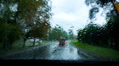 Rain droplets on car windshield . Look on the water drops on car windshield from inside the car at rain on the city street clipart