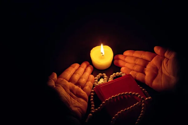 Praying hands, Islamic background . The holy Koran under candlelight . Book in candlelight