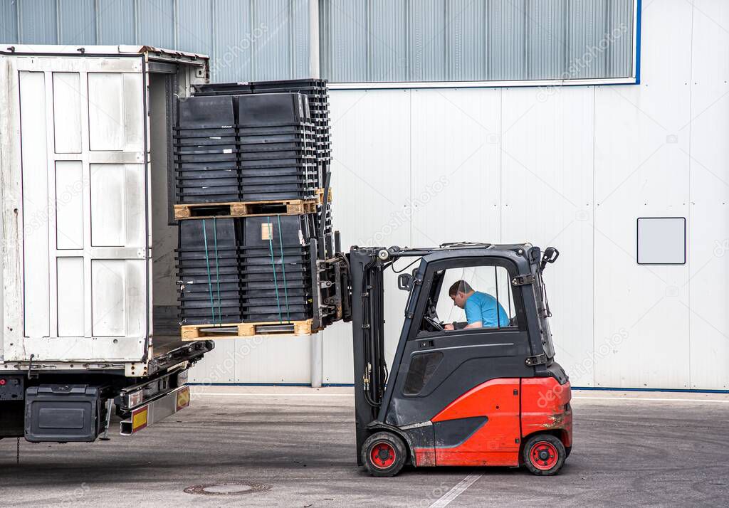 Unloading cargo from the truck  .  Loader operating forklift at warehouse